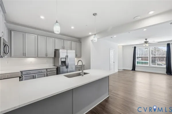a kitchen with stainless steel appliances a sink dishwasher a refrigerator and white cabinets with wooden floor