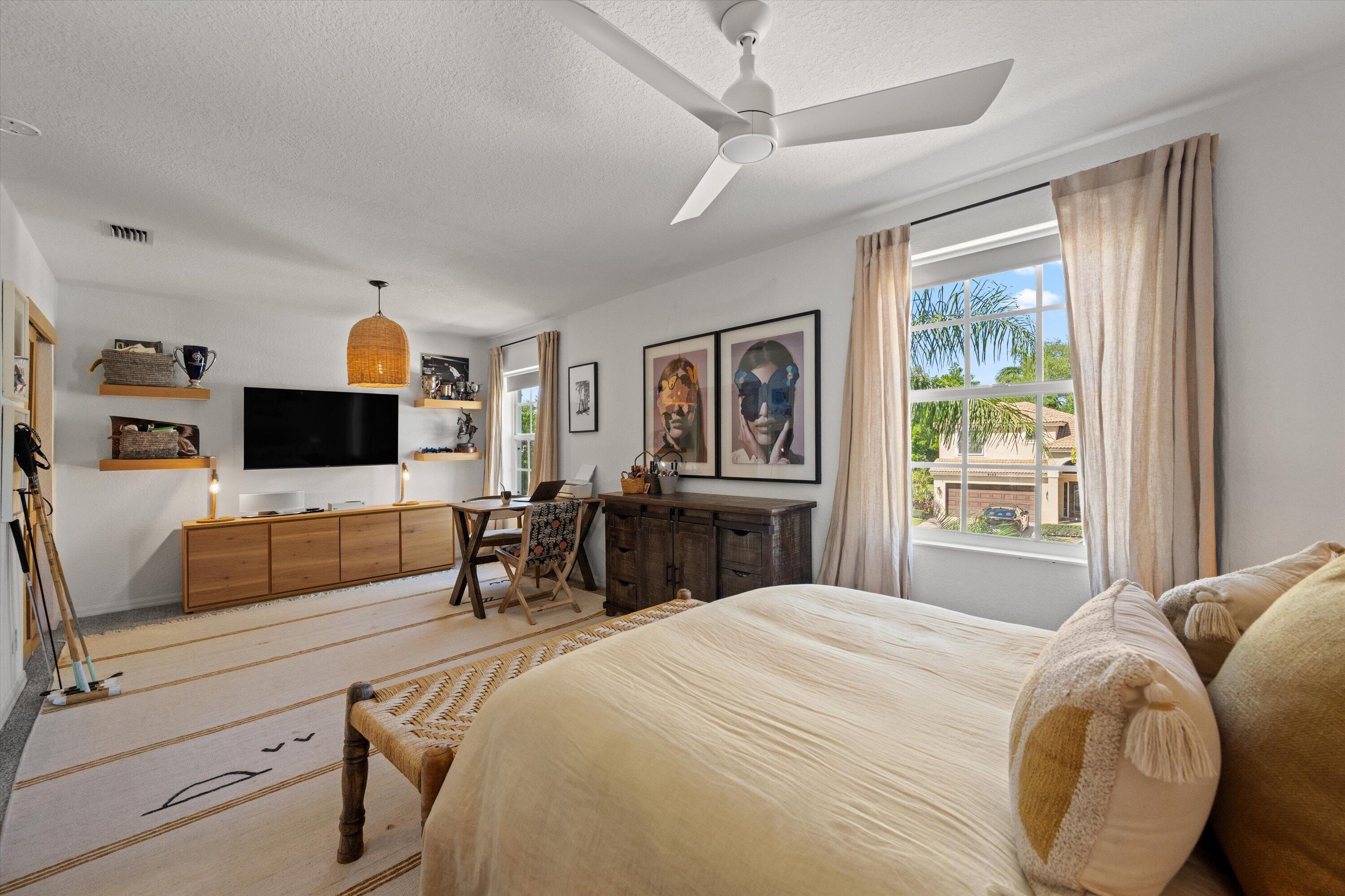 4138 Bluff Harbor Way Wellington, FL 33449 - Photo 31 of 48 a bedroom with a bed a flat screen tv and couches next to a window