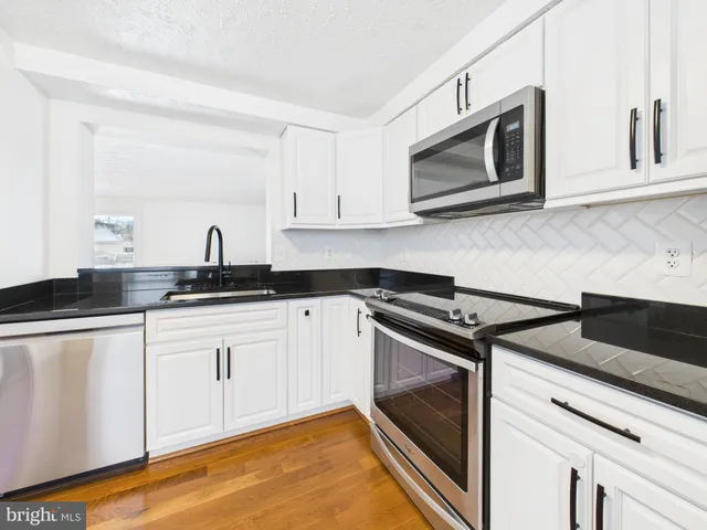a kitchen with granite countertop white cabinets stainless steel appliances and a sink