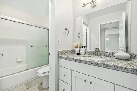 a bathroom with a granite countertop sink a toilet and shower