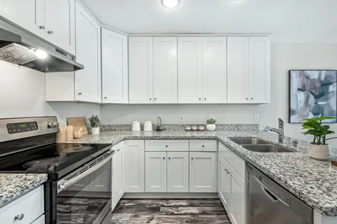 a kitchen with granite countertop a sink stainless steel appliances and cabinets