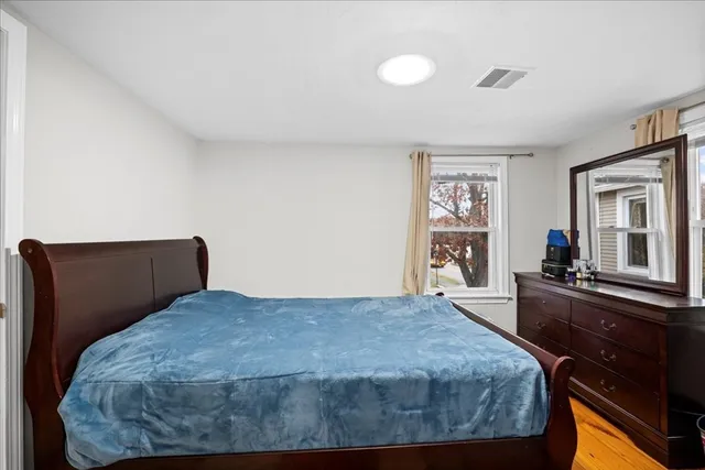 a bedroom with a bed and dresser with mirror