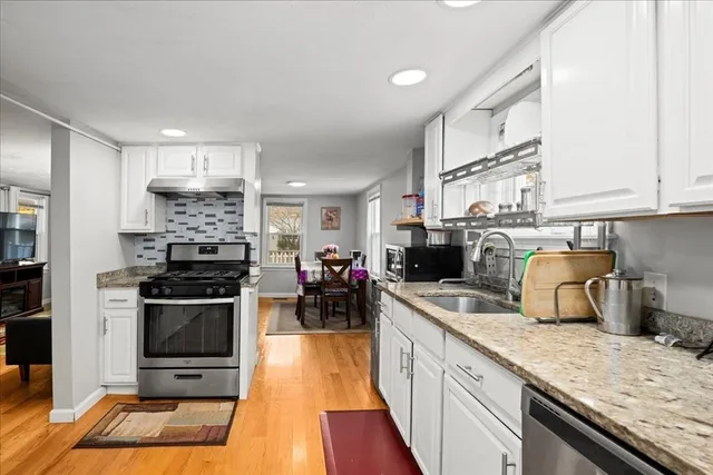 a kitchen with stainless steel appliances granite countertop a stove a sink and a microwave