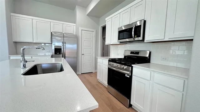 a view of kitchen with granite countertop cabinets and refrigerator