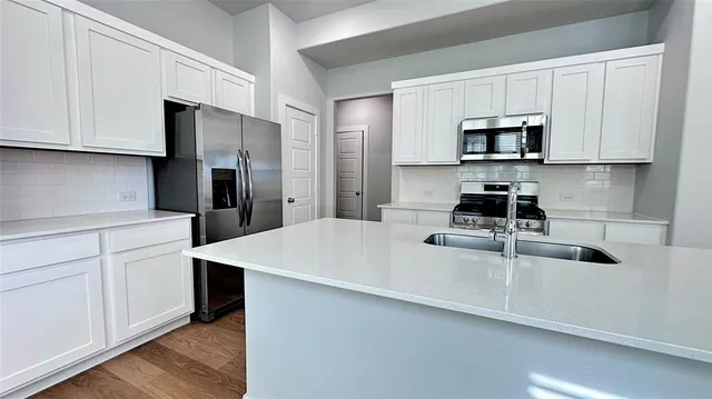 a kitchen with stainless steel appliances granite countertop a sink a stove a microwave and grey cabinets