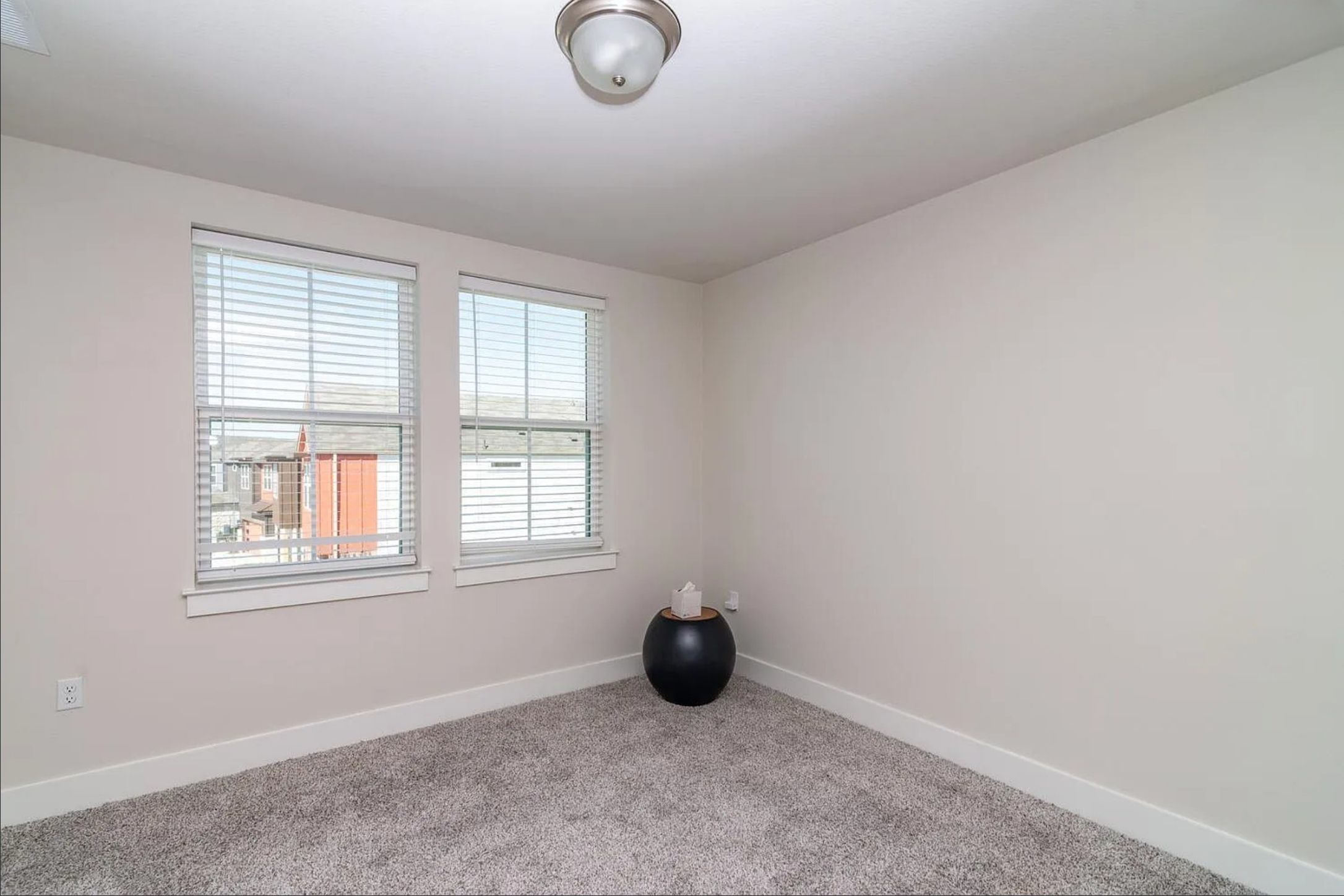 7501 Travertine Spring Drive Austin, TX 78744 - Photo 22 of 28 Bright room featuring two double-hung windows with blinds, neutral wall paint, and gray carpet flooring