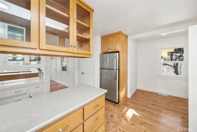 an empty room with windows and view of kitchen
