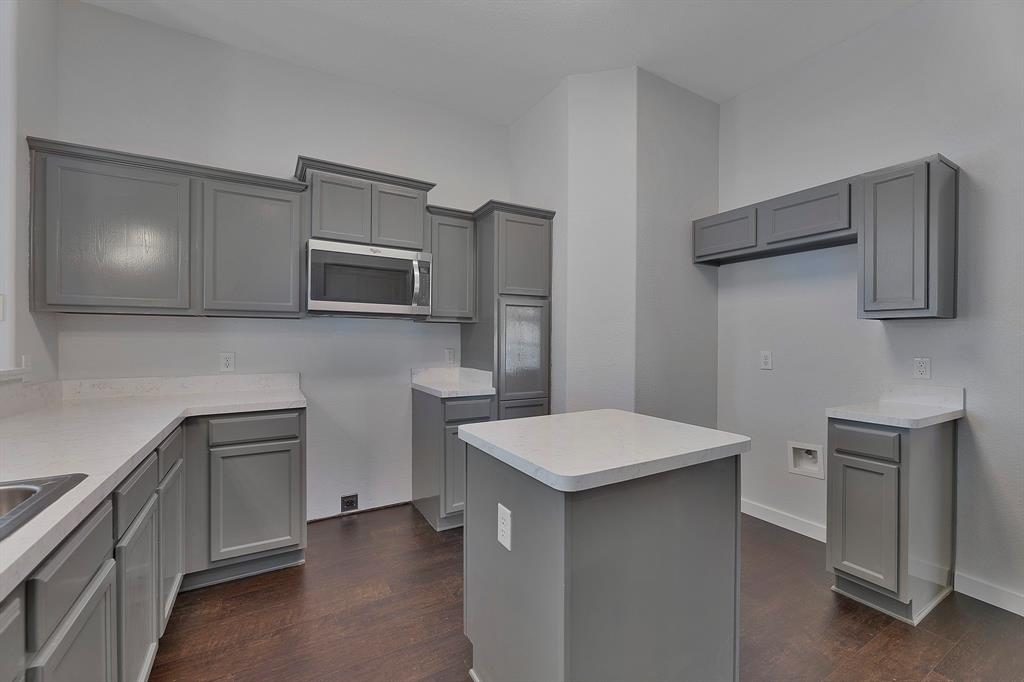 605 Clearbrook Street Azle, TX 76020 - Photo 9 of 33 Kitchen featuring a central island, gray cabinetry, light-toned countertops, and wood-finish flooring