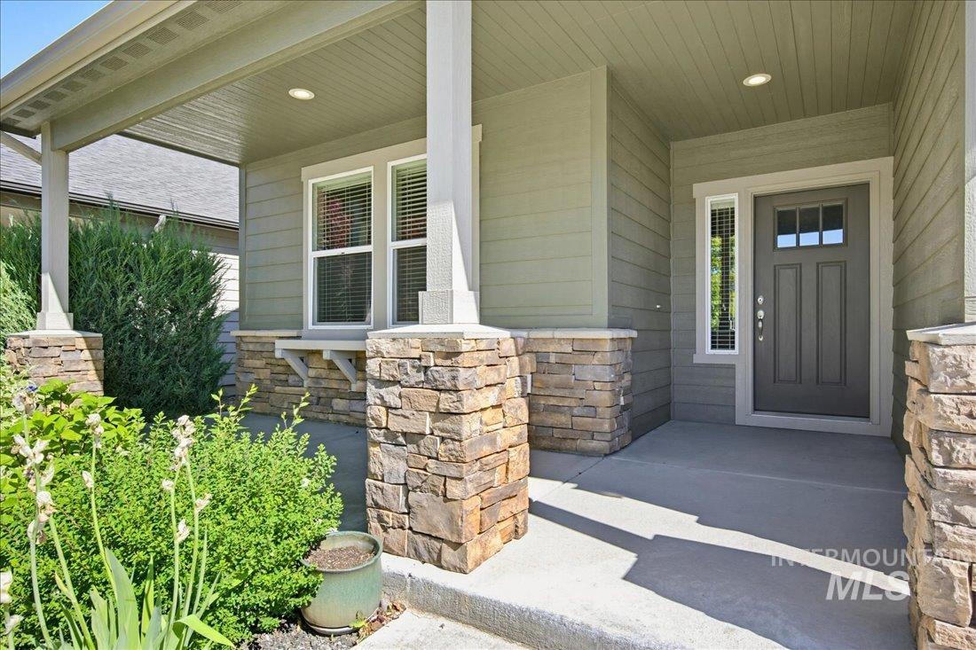 12460 West Azure Street Boise, ID 83713 - Photo 2 of 34 Covered front porch featuring stacked stone columns and a paneled entry door with decorative glass