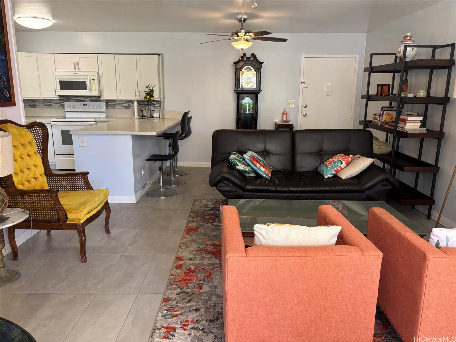 225 Kaʻiulani Avenue, Unit 402 Honolulu, HI 96815 - Photo 6 of 16 a living room with stainless steel appliances furniture a rug and a kitchen view