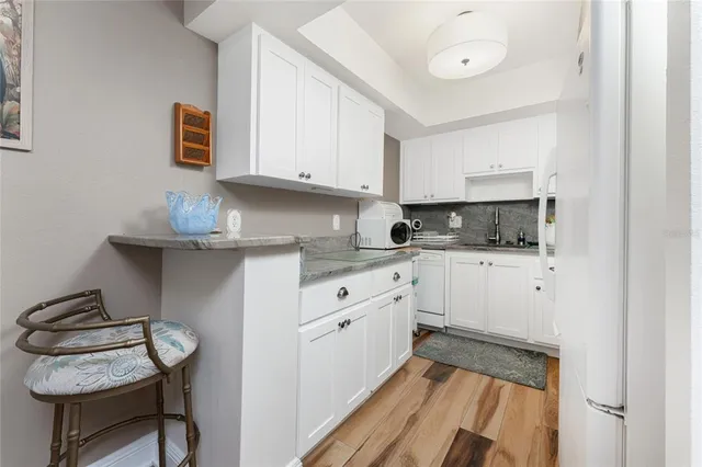 a kitchen with granite countertop white cabinets and white appliances