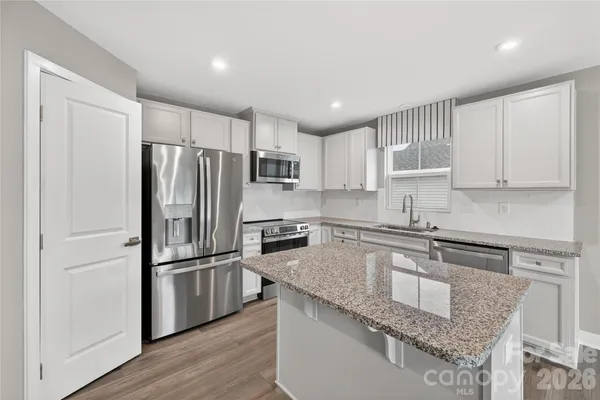 a kitchen with granite countertop a refrigerator and wooden cabinets