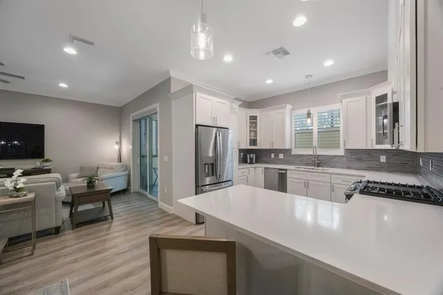 a kitchen with granite countertop a sink stainless steel appliances and white cabinets