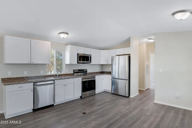 a kitchen with a sink cabinets stainless steel appliances and wooden floor