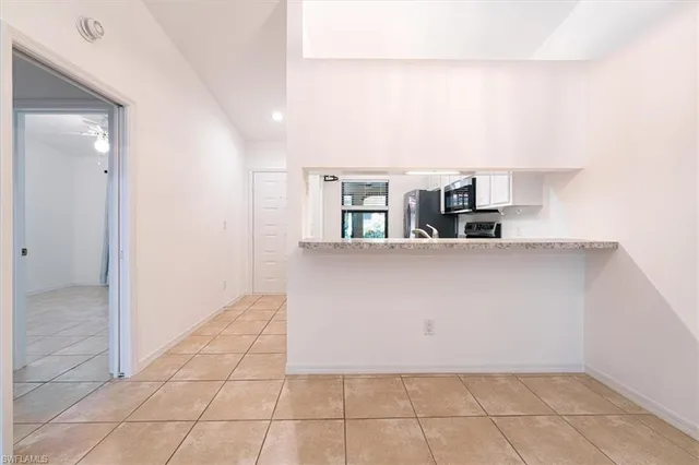 a view of a refrigerator in kitchen and an empty room