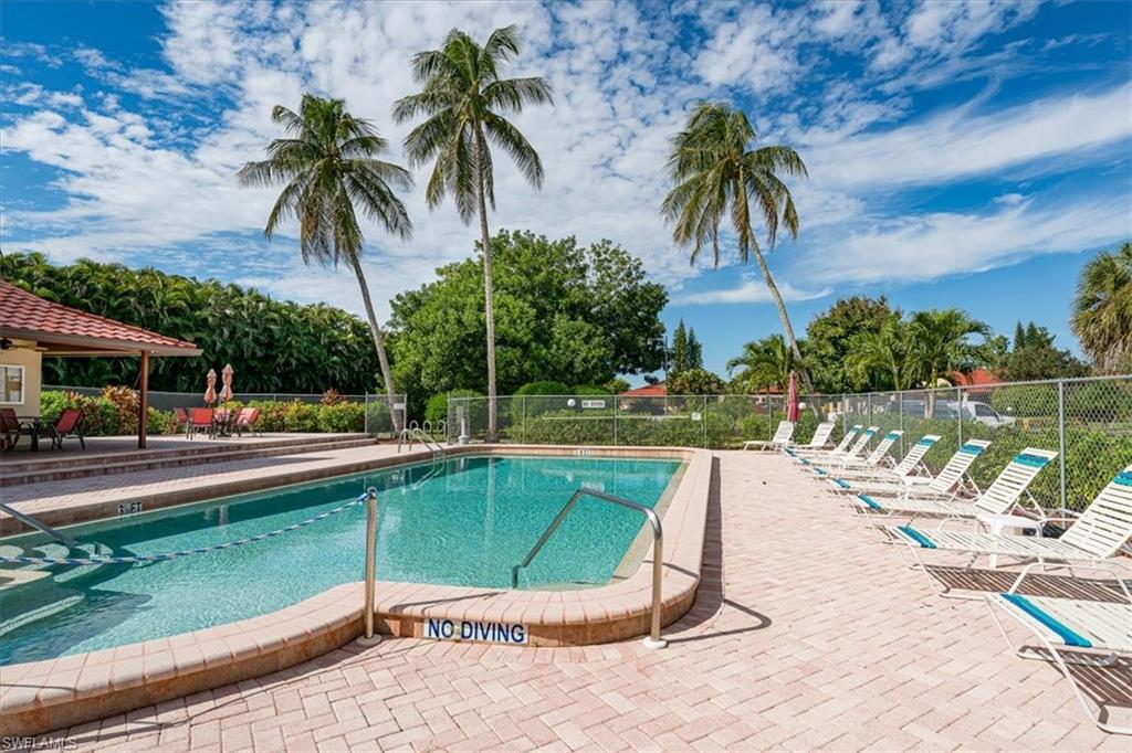 2009 Pine Isle Lane, Unit 2009 Naples, FL 34112 - Photo 32 of 33 a view of a swimming pool with a garden and palm trees
