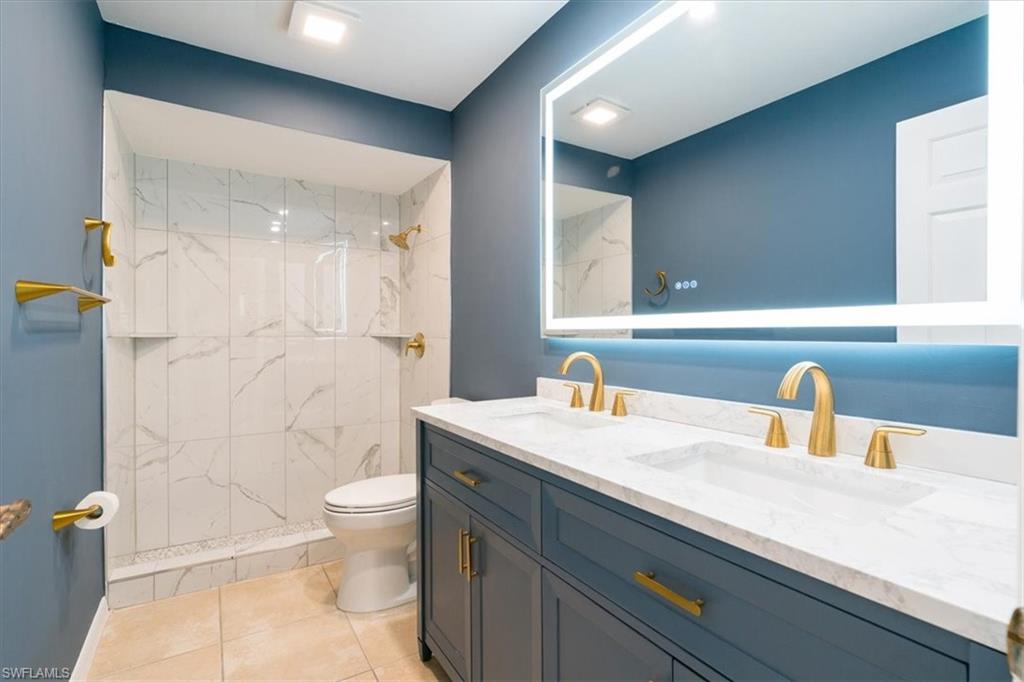 2009 Pine Isle Lane, Unit 2009 Naples, FL 34112 - Photo 6 of 33 a bathroom with a granite countertop sink a toilet a mirror and shower