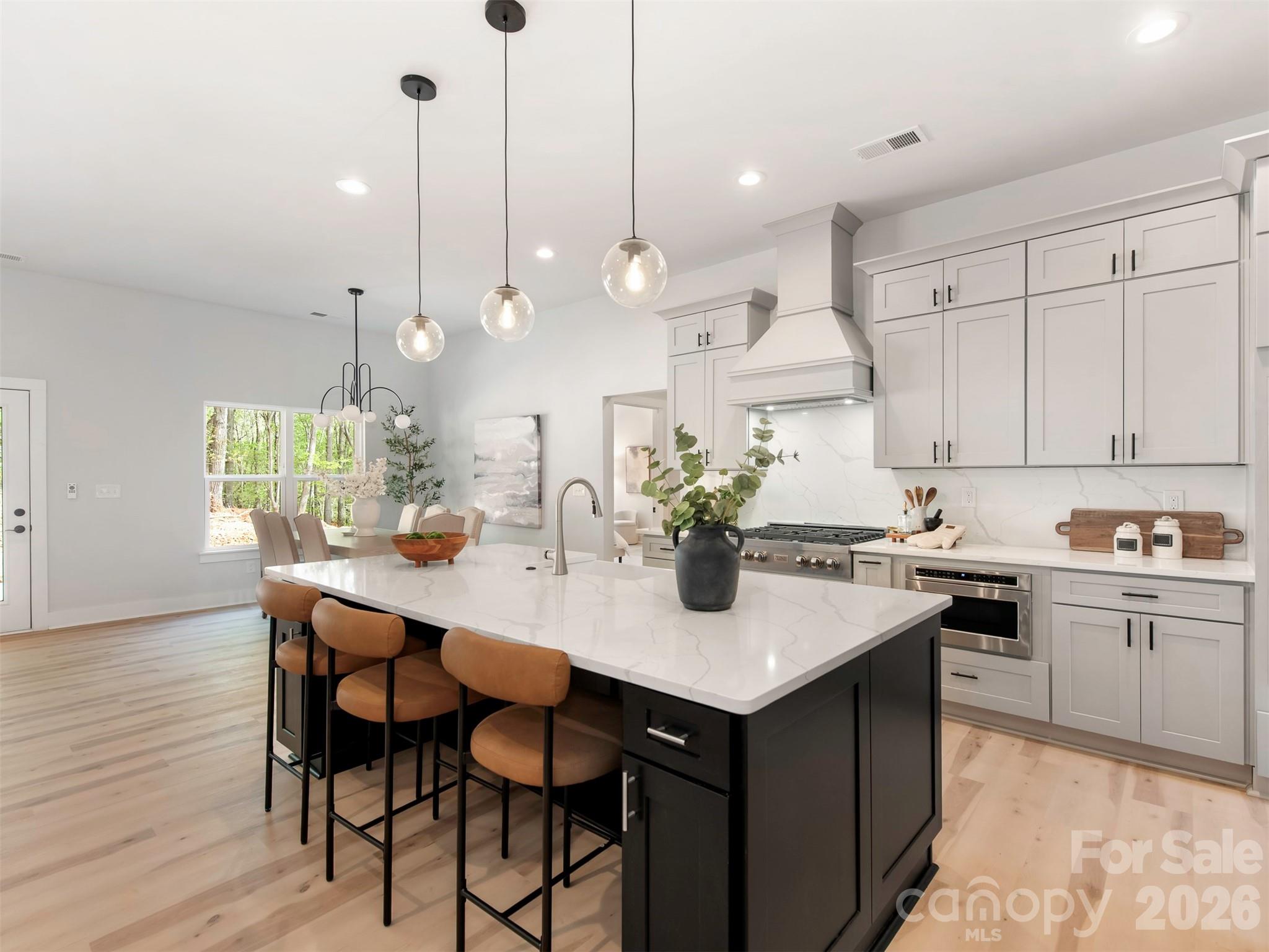 12133 Coyle Road Stanfield, NC 28163 - Photo 11 of 43 a kitchen with kitchen island granite countertop a sink a stove and chairs with wooden floor