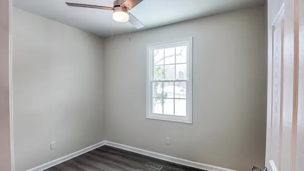an empty room with a window and ceiling fan