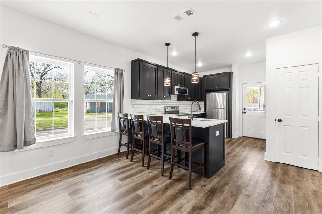 101 Ross Street Sulphur Springs, TX 75482 - Photo 7 of 29 a kitchen with stainless steel appliances kitchen island granite countertop a refrigerator a stove a sink a dining table and chairs with wooden floor