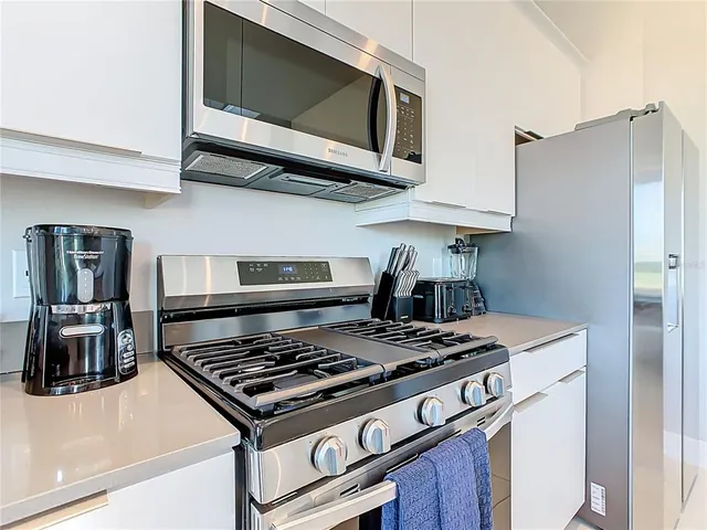 a kitchen with stainless steel appliances a table chairs refrigerator and microwave