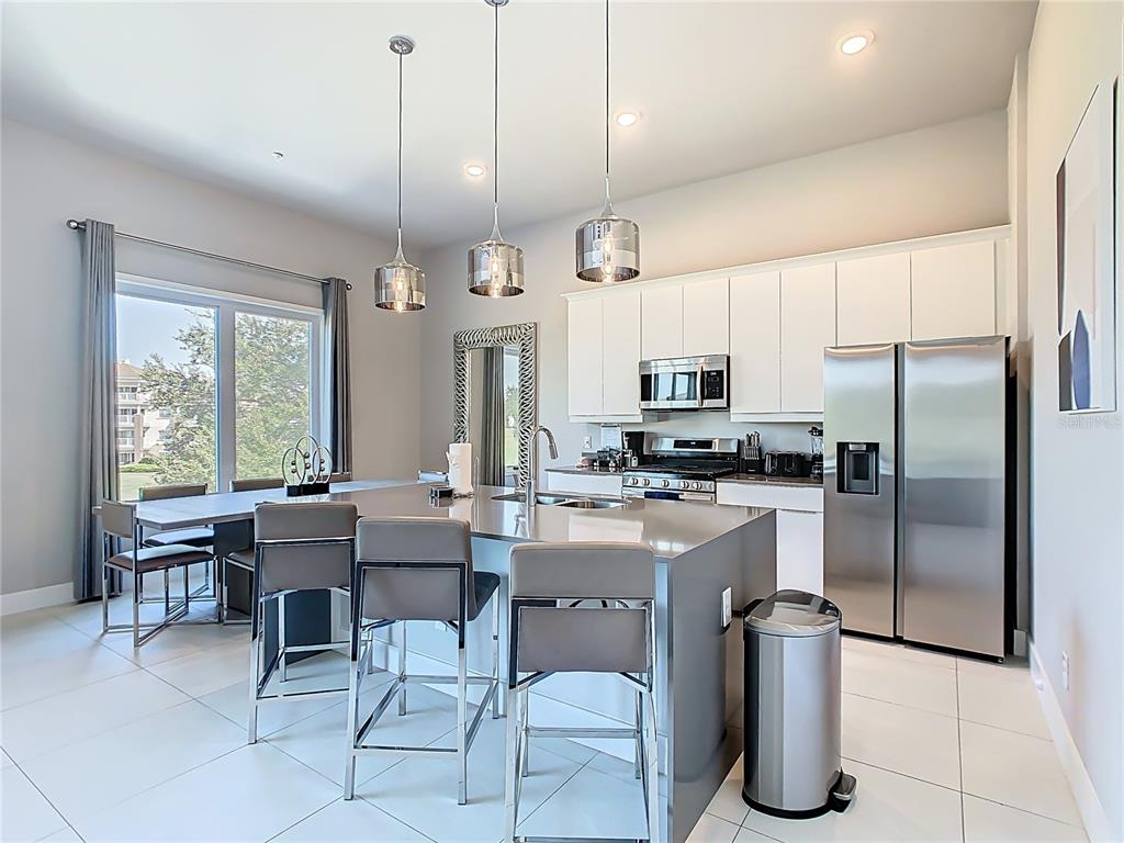 7740 Sandy Ridge Drive, Unit 245 Reunion, FL 34747 - Photo 16 of 57 a kitchen with stainless steel appliances a table chairs refrigerator and microwave