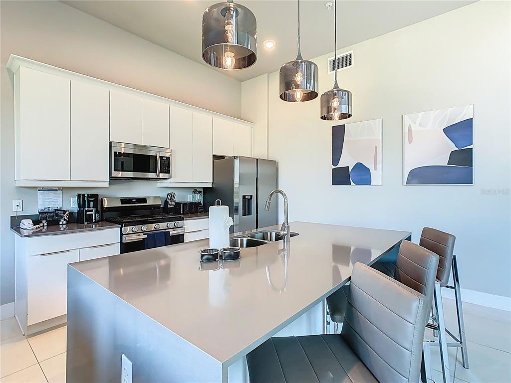 7740 Sandy Ridge Drive, Unit 245 Reunion, FL 34747 - Photo 8 of 57 a kitchen with stainless steel appliances granite countertop a sink a stove top oven a counter space and cabinets