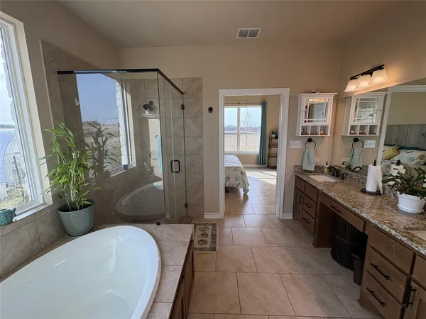 a large spacious bathroom with a granite countertop tub shower and mirror