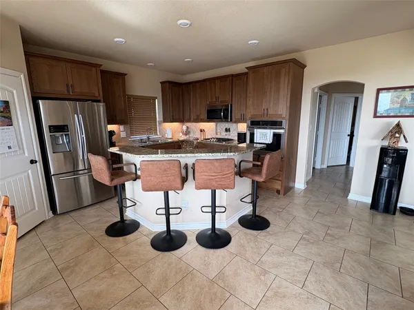a kitchen with stainless steel appliances kitchen island granite countertop a table chairs and a refrigerator