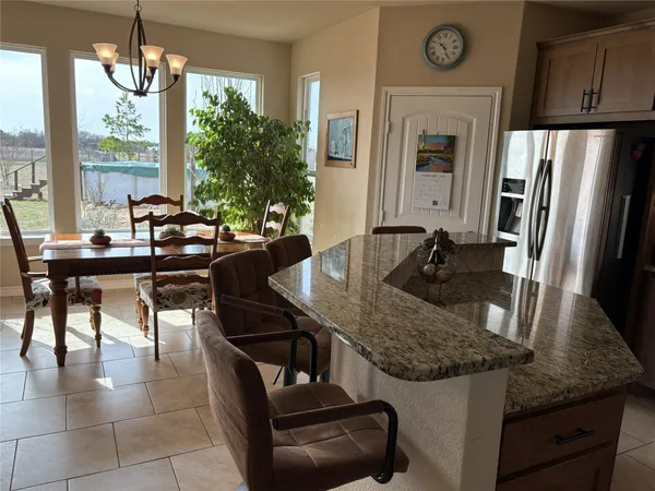 a kitchen with granite countertop a table chairs stove and refrigerator
