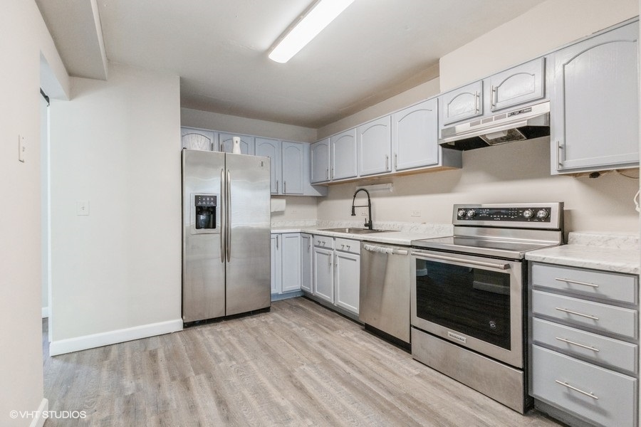 207 Walker Drive Bolingbrook, IL 60440 - Photo 6 of 18 a kitchen with cabinets stainless steel appliances and wooden floor