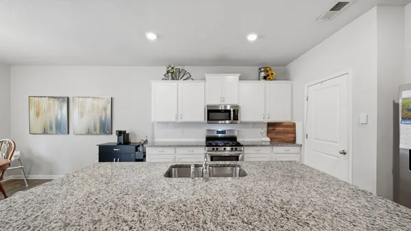 a living room with furniture a flat screen tv and kitchen view