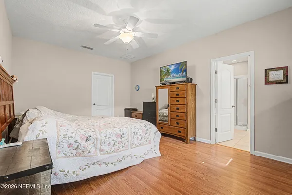 an empty room with wooden floor chandelier fan and windows