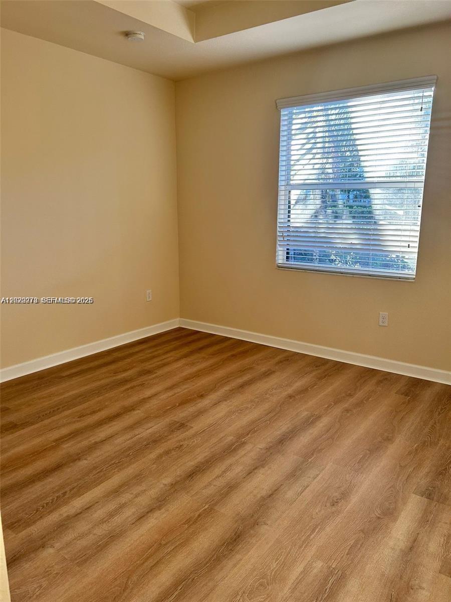 142 Northeast 28th Terrace, Unit 7 Homestead, FL 33033 - Photo 15 of 17 an empty room with wooden floor and windows