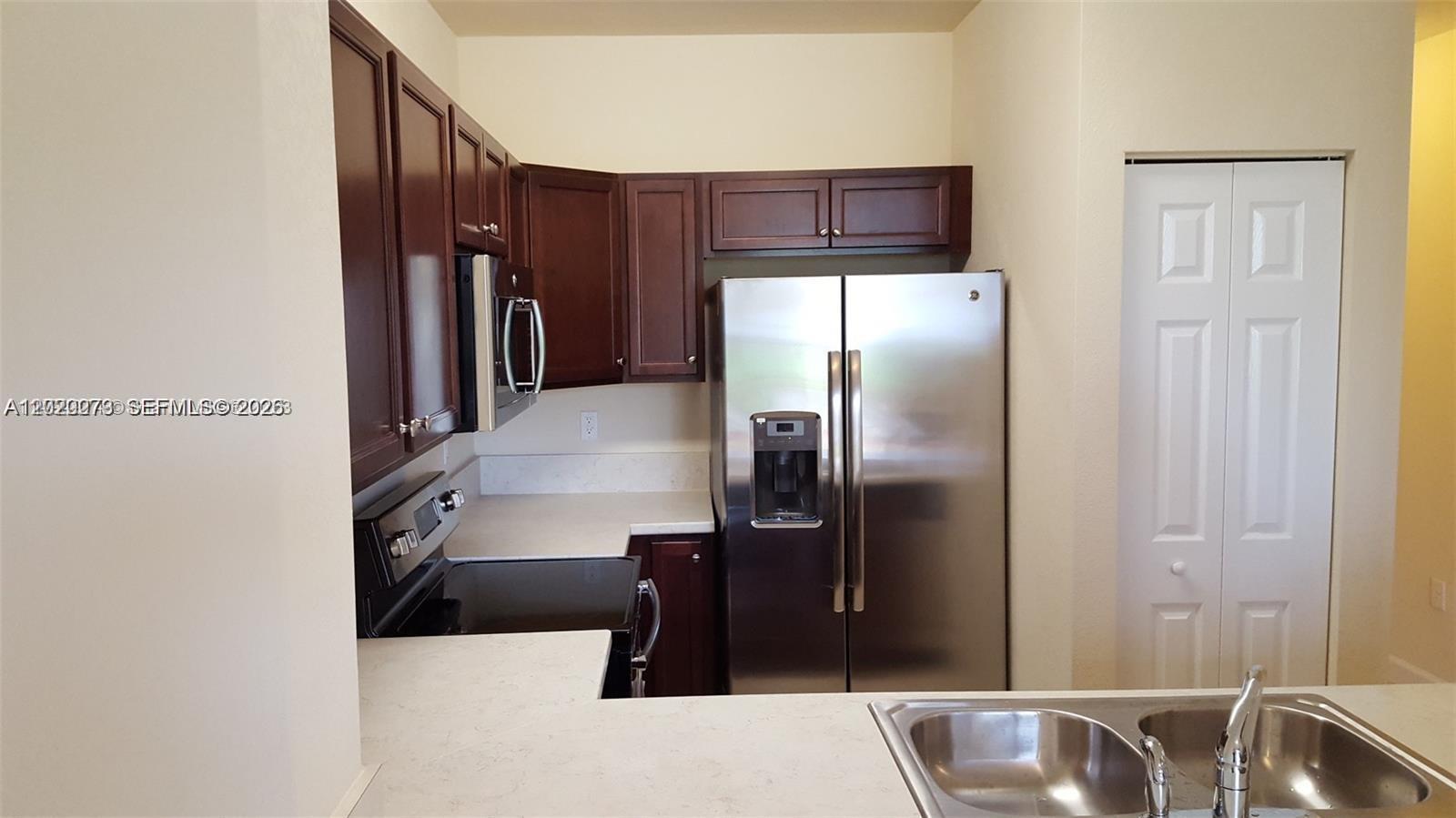 142 Northeast 28th Terrace, Unit 7 Homestead, FL 33033 - Photo 8 of 17 a kitchen with stainless steel appliances a refrigerator and a sink