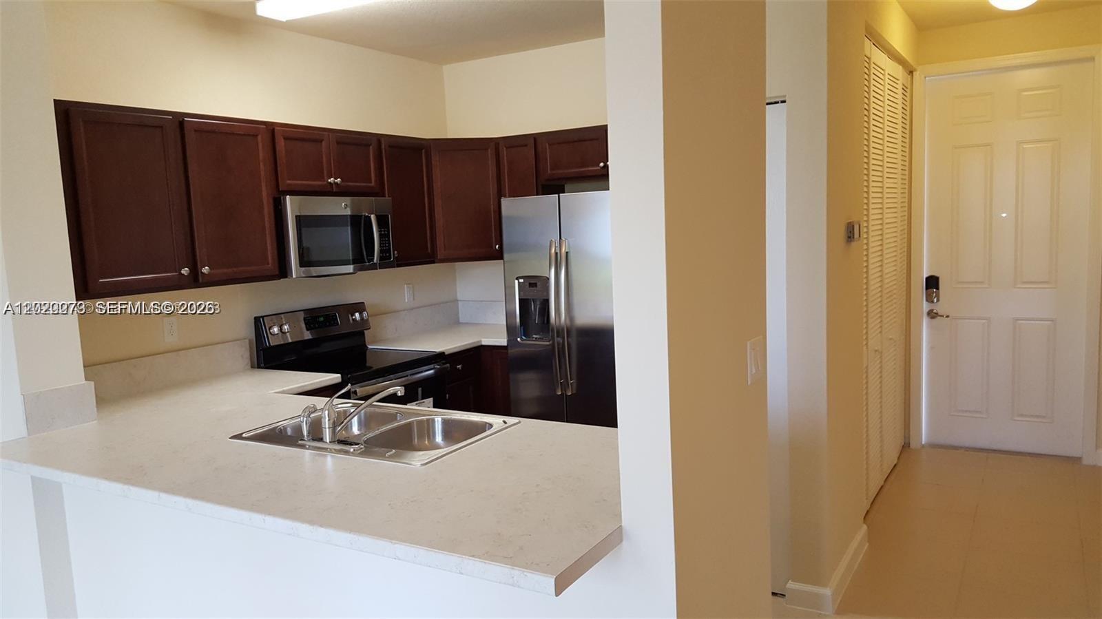 142 Northeast 28th Terrace, Unit 7 Homestead, FL 33033 - Photo 9 of 17 a kitchen with a sink a microwave a refrigerator and cabinets