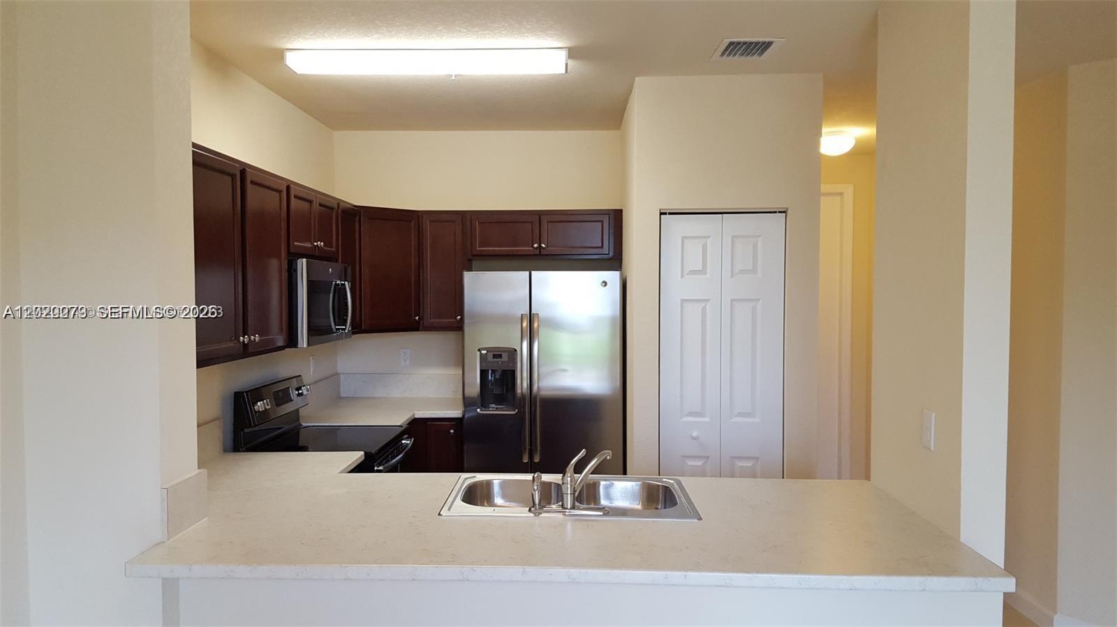 142 Northeast 28th Terrace, Unit 7 Homestead, FL 33033 - Photo 10 of 17 a kitchen with stainless steel appliances granite countertop a refrigerator and a sink