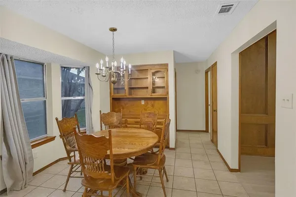 an empty room with a chandelier fan and wooden floor