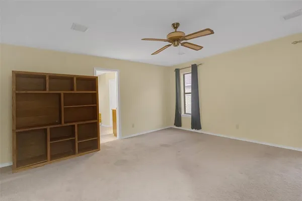 a view of an empty room with chandelier fan and a window