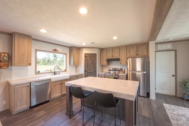 a kitchen with stainless steel appliances a dining table chairs and wooden floor