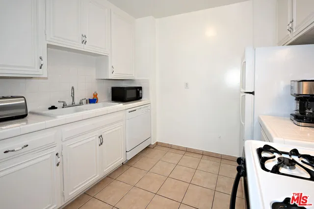 a kitchen with white cabinets and appliances