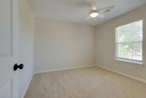 an empty room with a ceiling fan and a window