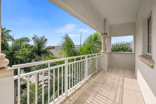 a view of a white building with large windows and plants