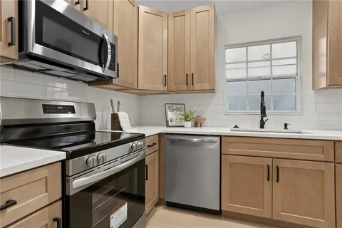 a kitchen with cabinets stainless steel appliances and a window