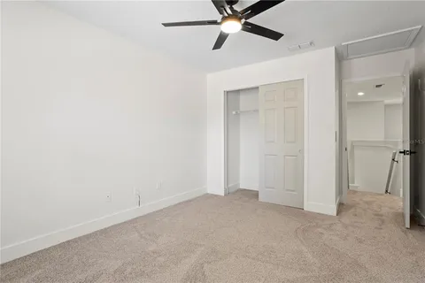 an empty room with closet and a chandelier fan