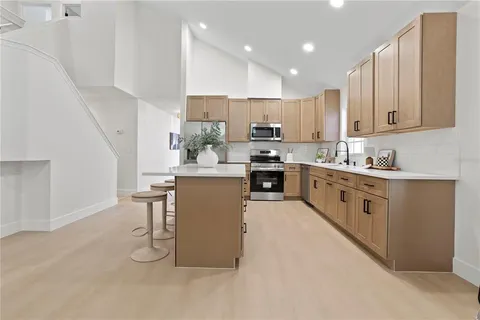 a kitchen with kitchen island granite countertop a sink cabinets and stainless steel appliances