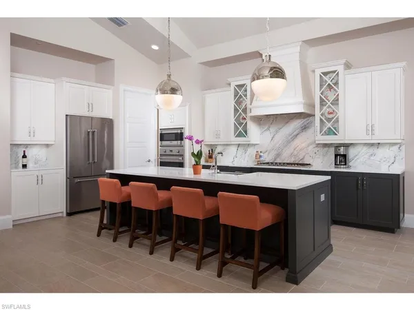 a kitchen with stainless steel appliances granite countertop a table chairs sink refrigerator and cabinets