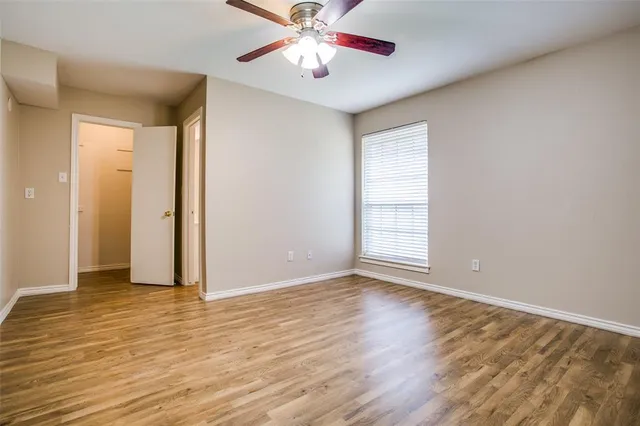 a view of an empty room with window and wooden floor