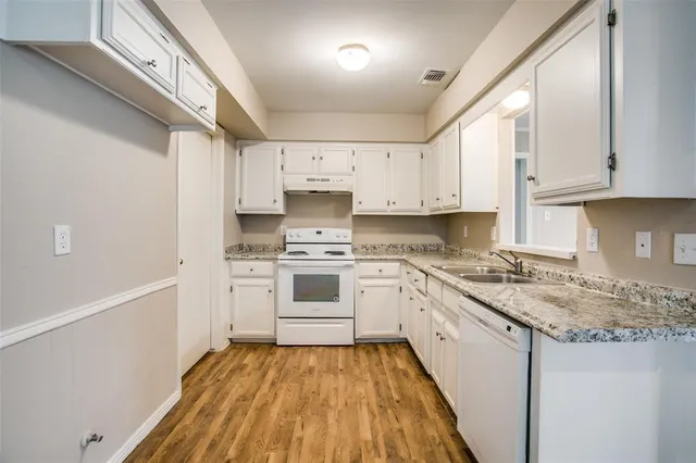 a kitchen with granite countertop white cabinets and white appliances