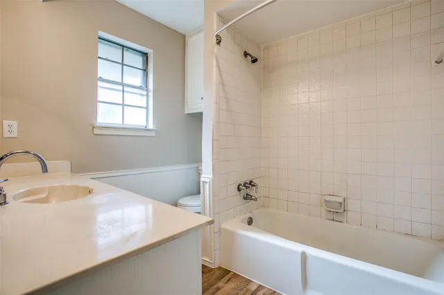a bathroom with a granite countertop sink a bathtub and window